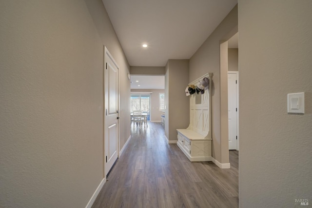 corridor featuring baseboards, recessed lighting, dark wood finished floors, and a textured wall
