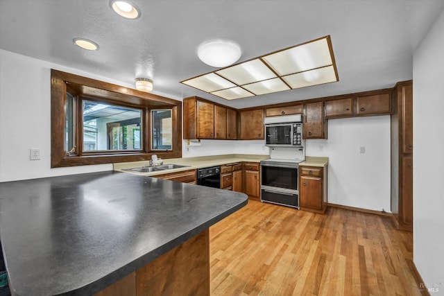 kitchen with a peninsula, a sink, black dishwasher, range with electric cooktop, and stainless steel microwave