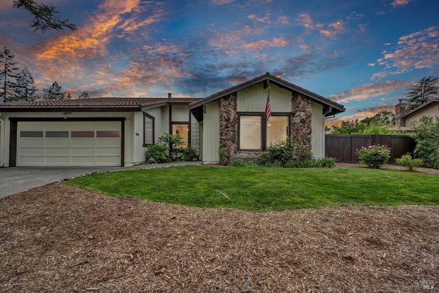 view of front of property featuring a garage, driveway, fence, and a front yard