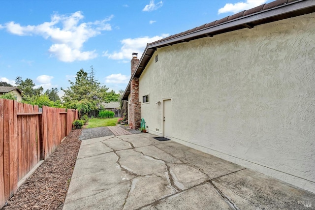 view of home's exterior featuring a chimney, a patio area, stucco siding, and a fenced backyard