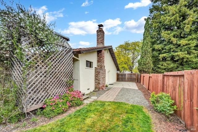 view of property exterior with a chimney, a patio area, stucco siding, and a fenced backyard