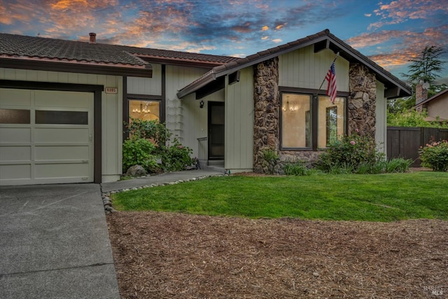 view of front of home with a garage, a tile roof, fence, a front lawn, and concrete driveway