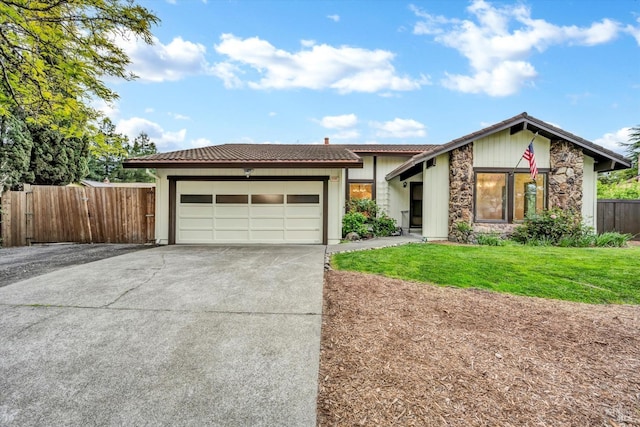 view of front facade with concrete driveway, a tile roof, fence, and an attached garage