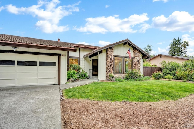 view of front of home featuring a garage, a tiled roof, fence, a front lawn, and driveway