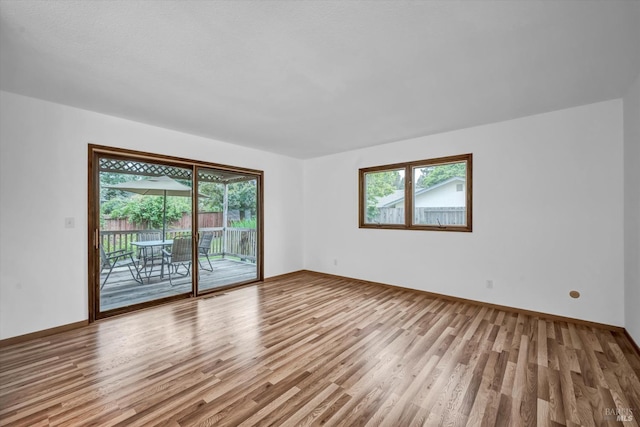 empty room with baseboards, plenty of natural light, and wood finished floors