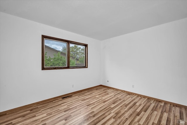 unfurnished room with baseboards, visible vents, and wood finished floors
