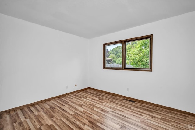 empty room featuring baseboards, visible vents, and wood finished floors
