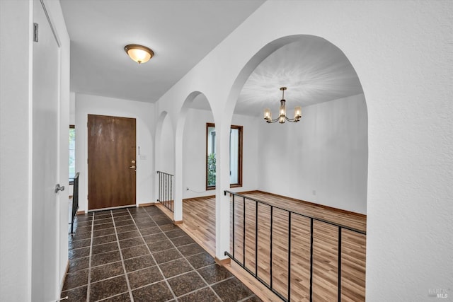 foyer featuring plenty of natural light, a chandelier, and baseboards
