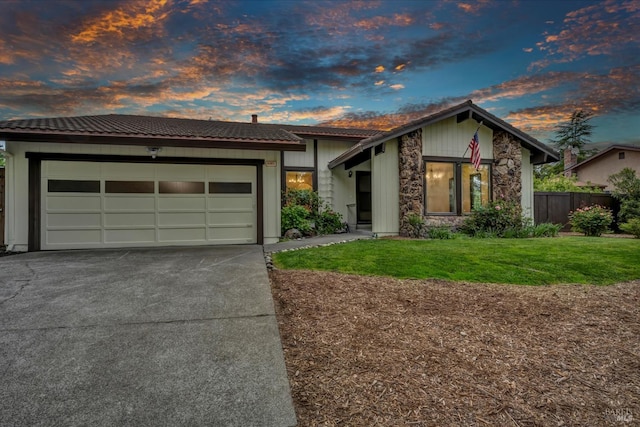 view of front facade with fence, a garage, a tile roof, concrete driveway, and a front yard
