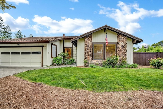 view of front facade with an attached garage, stone siding, fence, concrete driveway, and a front yard