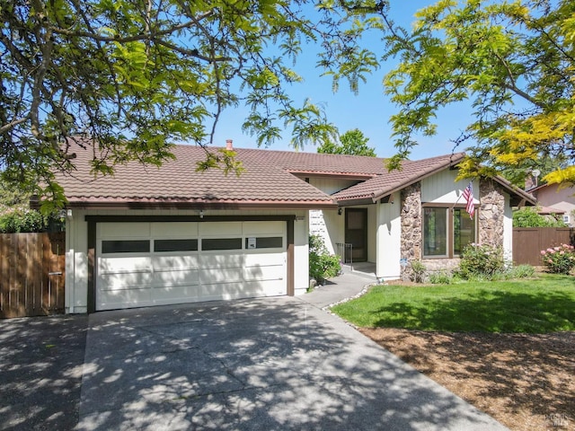 view of front of house featuring a tile roof, fence, stone siding, and concrete driveway