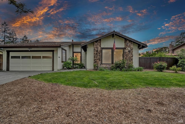 view of front of home with a lawn, driveway, an attached garage, and fence