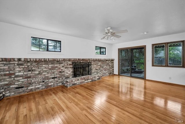 unfurnished living room featuring a ceiling fan, baseboards, a fireplace, and wood finished floors