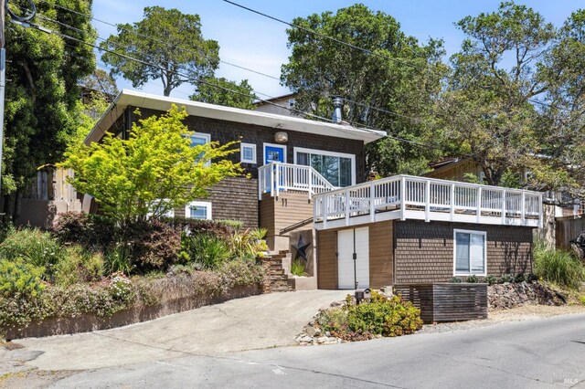 view of front facade featuring a wooden deck, central AC unit, concrete driveway, and stairway