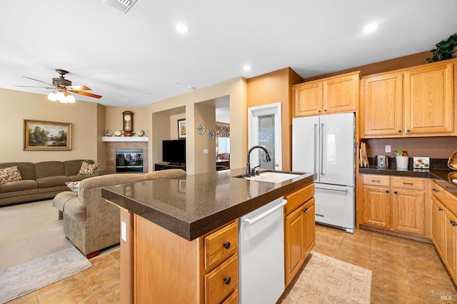 kitchen with a sink, dark countertops, light tile patterned floors, and white appliances