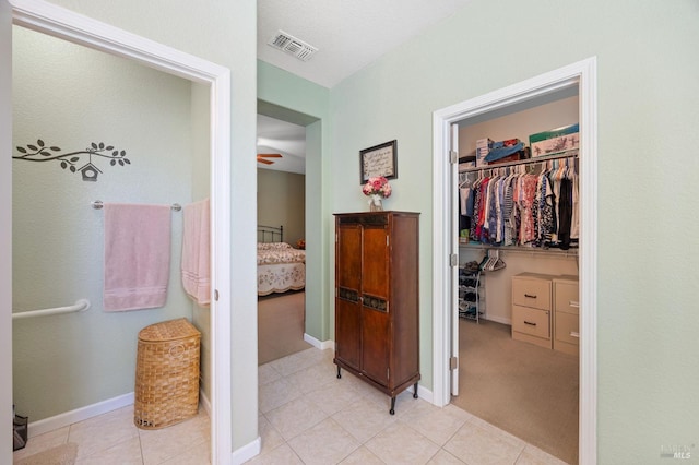 ensuite bathroom with tile patterned floors, a walk in closet, ensuite bath, and visible vents