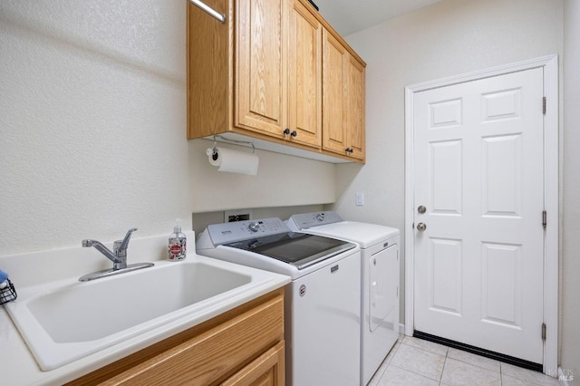 clothes washing area with a sink, light tile patterned floors, independent washer and dryer, and cabinet space