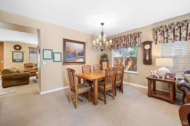 dining room featuring an inviting chandelier, baseboards, and light carpet