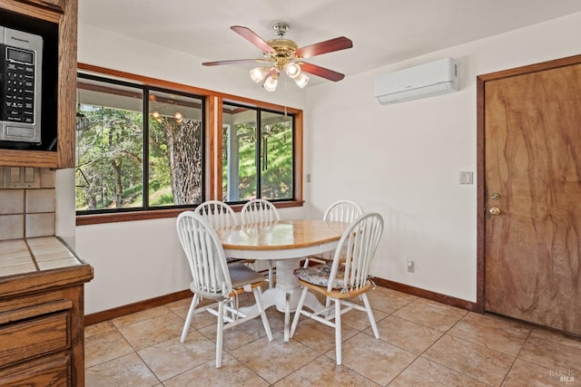 dining area featuring ceiling fan, baseboards, a wall mounted AC, and light tile patterned floors