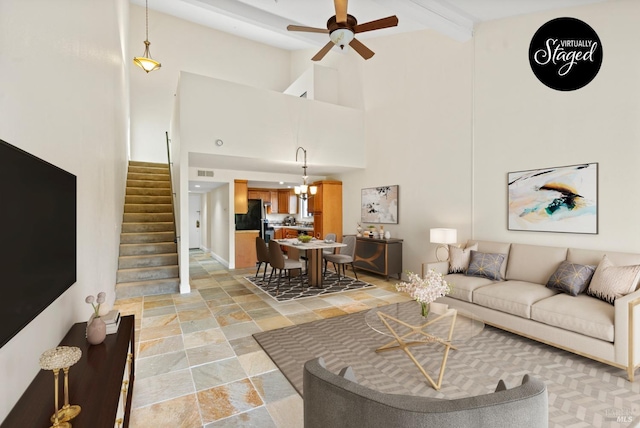 living room featuring stone finish floor, visible vents, stairway, high vaulted ceiling, and ceiling fan with notable chandelier