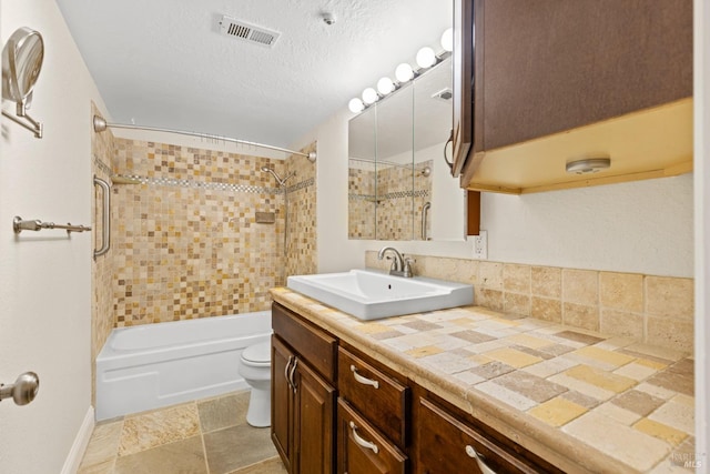 full bath with a textured ceiling, visible vents, shower / washtub combination, vanity, and toilet
