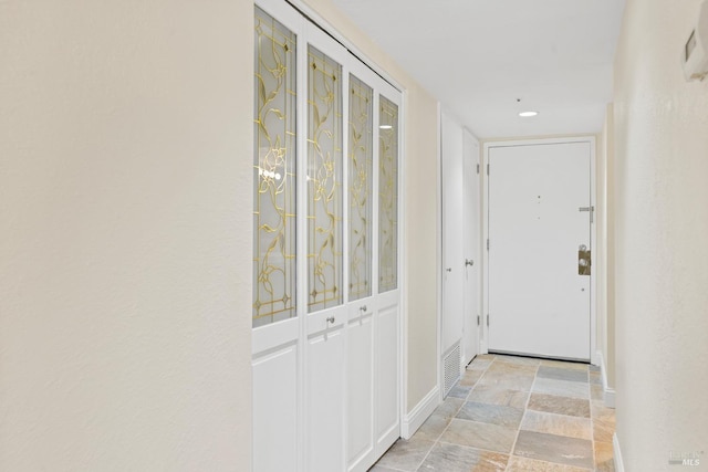 hallway featuring baseboards and stone finish flooring