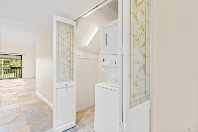 clothes washing area with laundry area, stacked washer and dryer, and stone tile floors