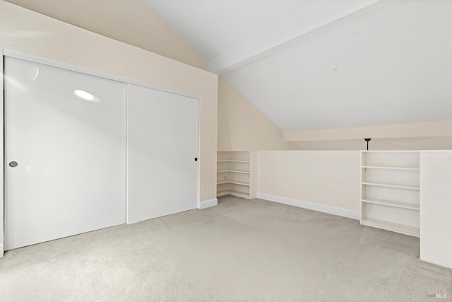 bonus room featuring baseboards, light carpet, built in shelves, and lofted ceiling