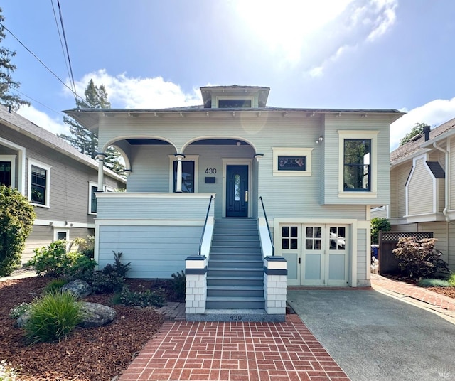 view of front of property with an attached garage, stairway, aphalt driveway, and covered porch
