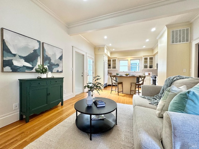 living area with visible vents, light wood-style floors, and crown molding