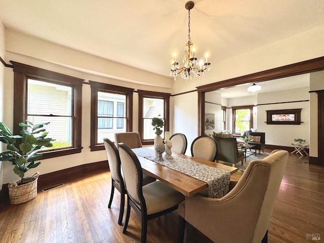 dining room featuring baseboards, wood finished floors, visible vents, and an inviting chandelier