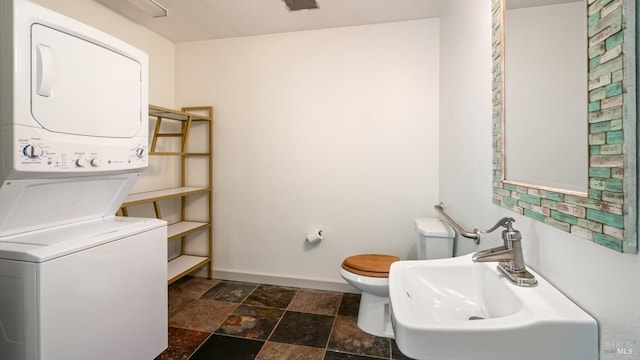 3880 Doris Murphy Ct, Occidental, CA 95465 - bathroom with stacked washing machine and dryer, toilet, a sink, stone finish flooring, and baseboards
