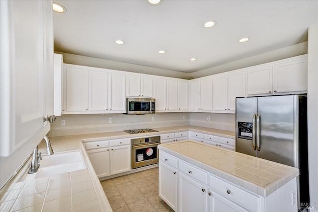 kitchen with stainless steel appliances, a sink, recessed lighting, and tile countertops
