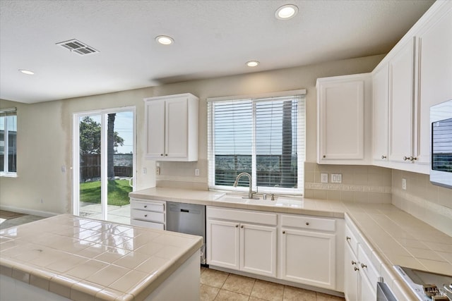 kitchen featuring tile countertops, backsplash, dishwasher, and a sink