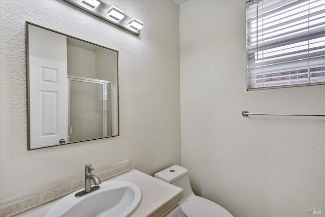 full bath with a textured wall, vanity, a shower stall, and toilet