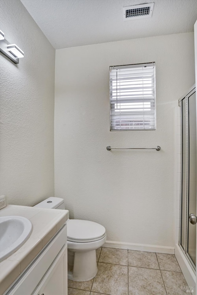bathroom featuring toilet, visible vents, tile patterned flooring, a shower stall, and vanity