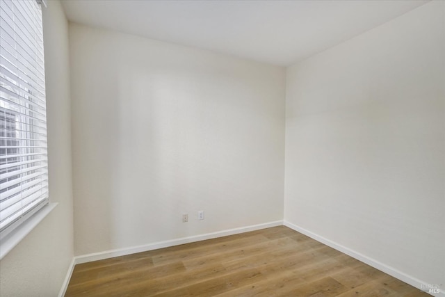 spare room featuring baseboards and light wood-style floors
