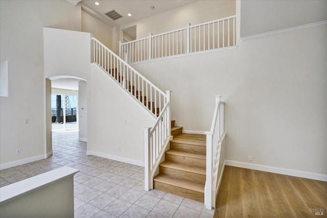 stairs featuring arched walkways, visible vents, baseboards, and recessed lighting