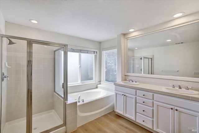 full bathroom with wood finished floors, a garden tub, a stall shower, and a sink