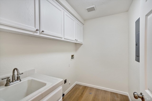 laundry area featuring a sink, light wood-type flooring, cabinet space, baseboards, and visible vents