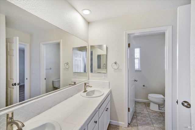 full bath with a sink, double vanity, and toilet