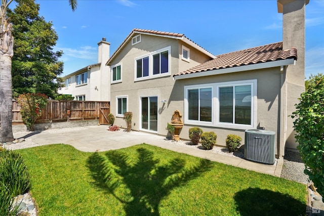back of property featuring central AC unit, a fenced backyard, a yard, a patio, and stucco siding