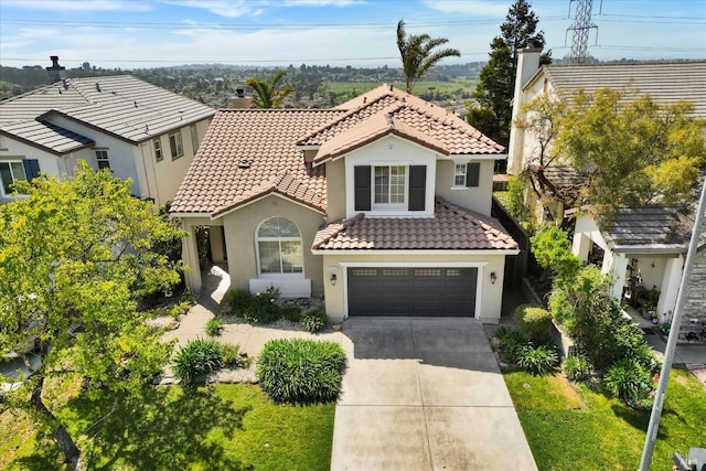mediterranean / spanish-style house with stucco siding, an attached garage, a tile roof, and concrete driveway