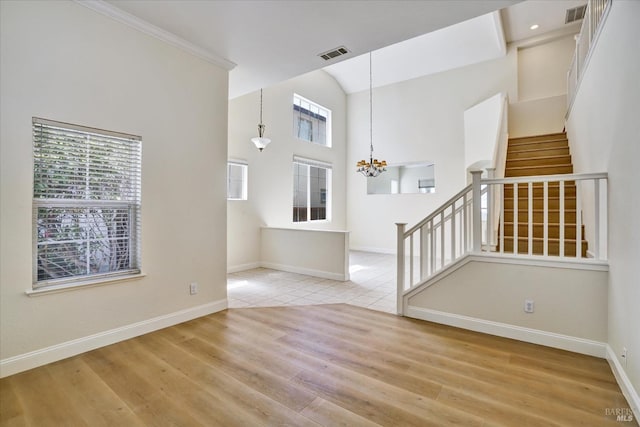 unfurnished living room featuring visible vents, stairway, and a healthy amount of sunlight