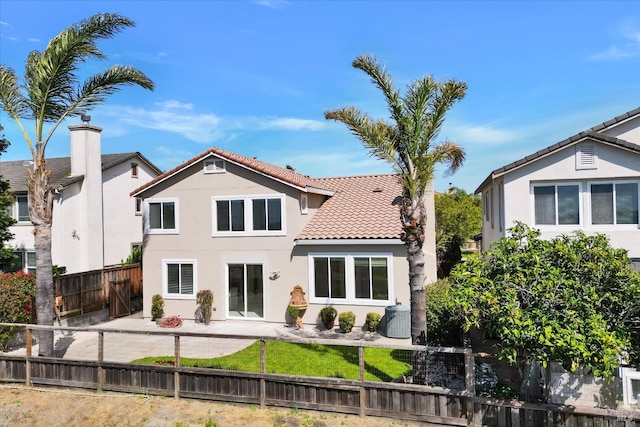 rear view of property with a tile roof, cooling unit, fence private yard, a patio, and stucco siding
