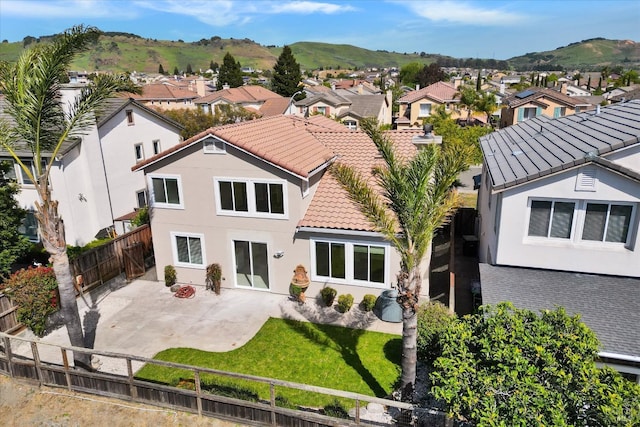 rear view of property with a fenced backyard, a residential view, and a tiled roof