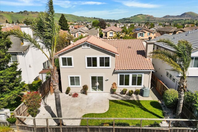 rear view of house featuring a fenced backyard, a patio, a residential view, and a tiled roof