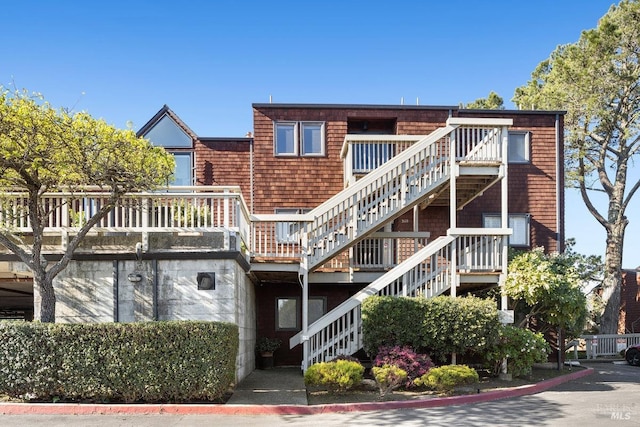 rear view of property featuring a wooden deck and stairs