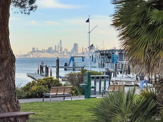 surrounding community with a lawn, a water view, a boat dock, and a view of city