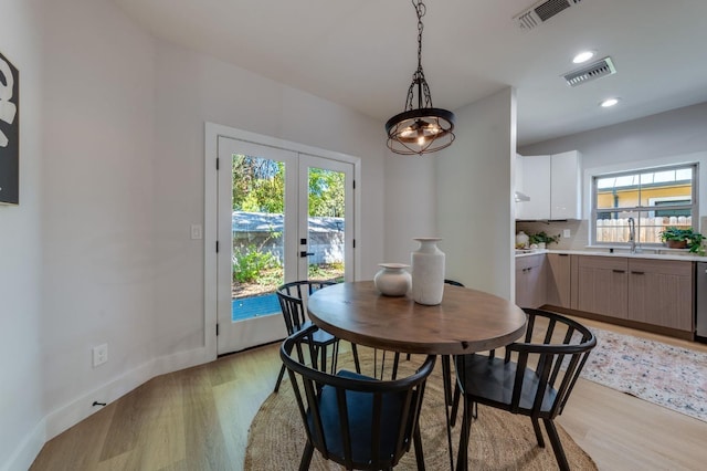 dining space with light wood-style flooring, visible vents, and a wealth of natural light